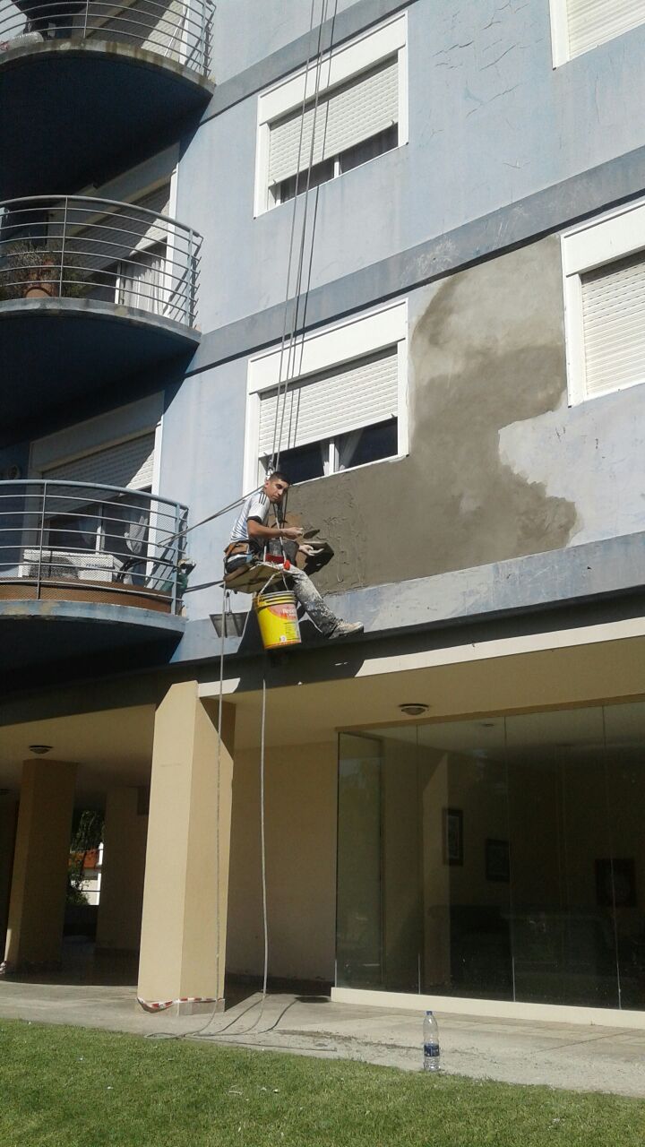 Reparación altura edificio, técnico silletero realizando albañilería